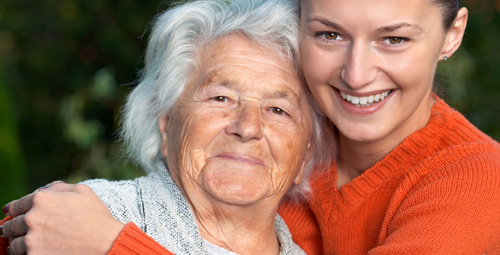 An old woman being hugged by a carer