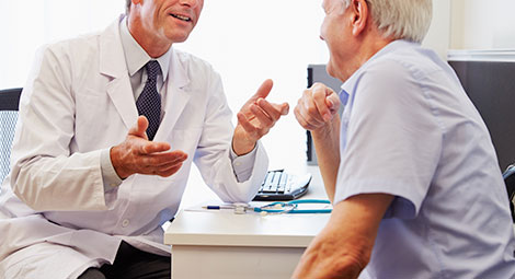 An older man speaking with a GP
