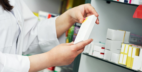 A pharmacist holding a box of medication